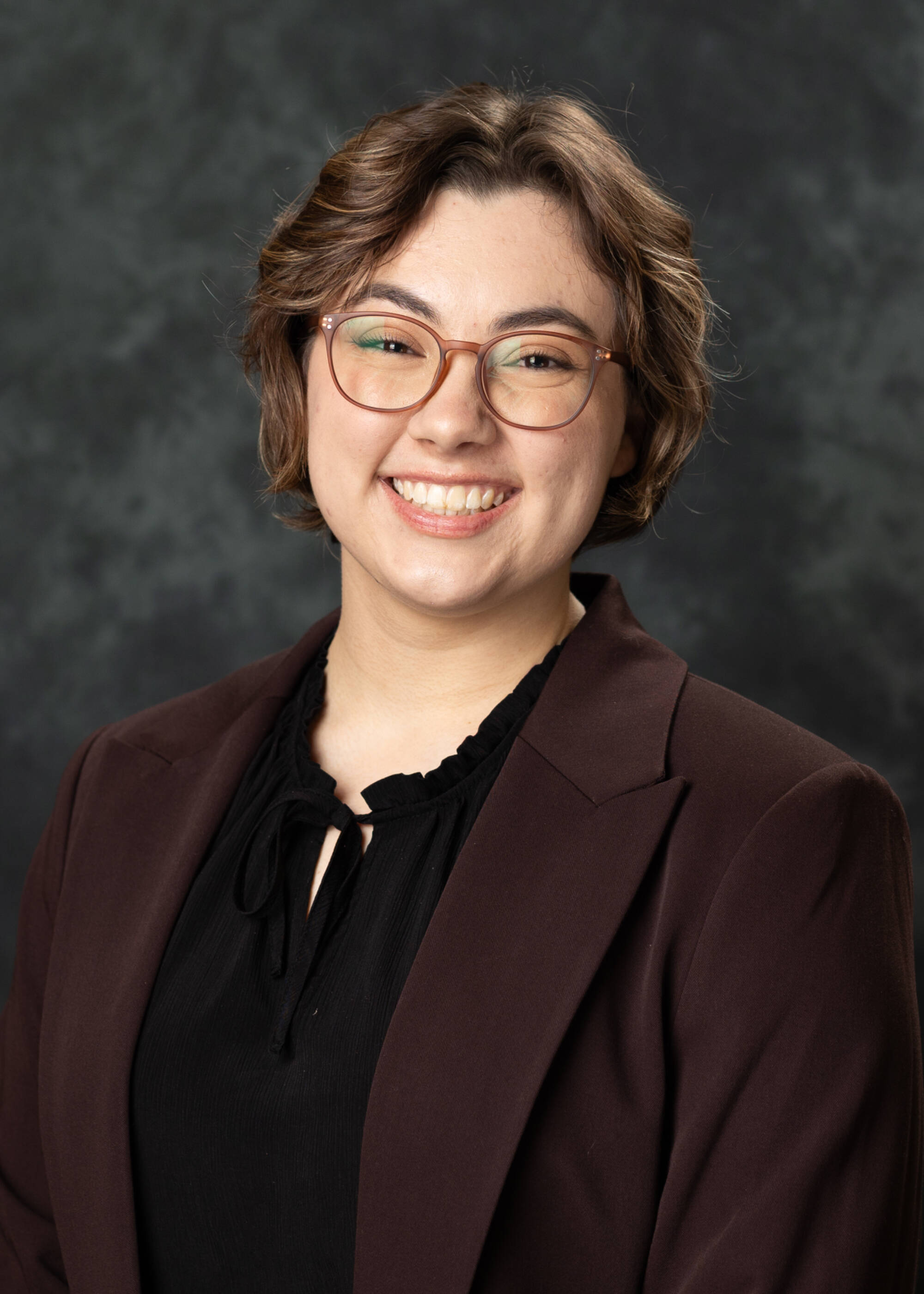 Sophie Gemmen smiling in a brown blazer and black shirt